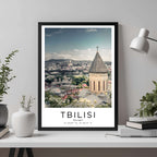 A framed travel poster of Tbilisi displayed on a wall in a home office, adding an element of professional and artistic flair.